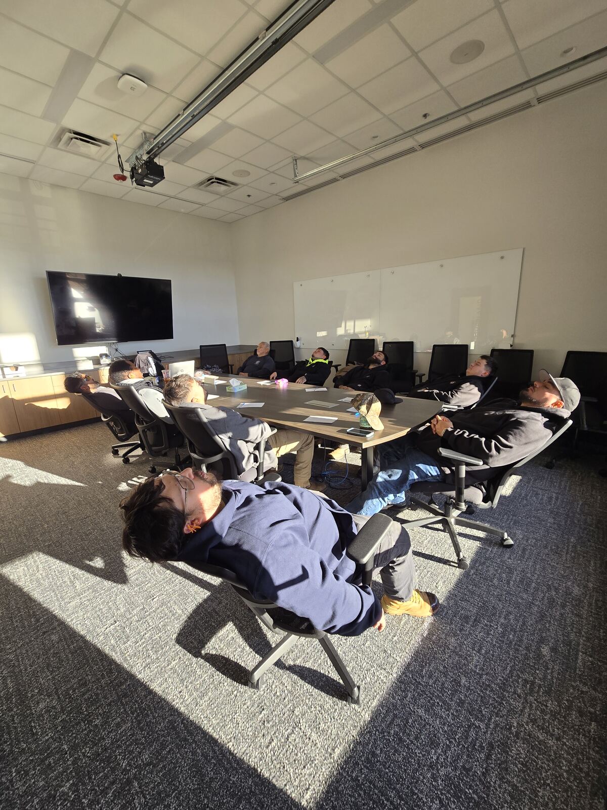 A full conference table of staff relaxing during an on-site Mobile Stress Recovery session